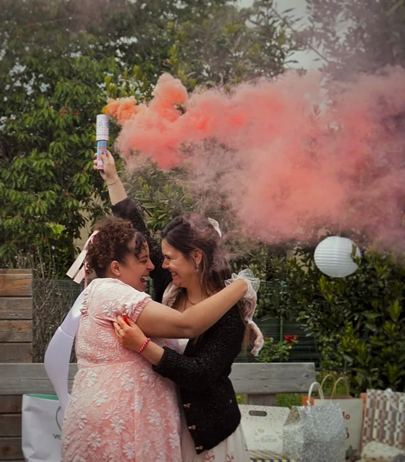 Un couple s’enlace pendant une célébration dans un nuage de fumée rose