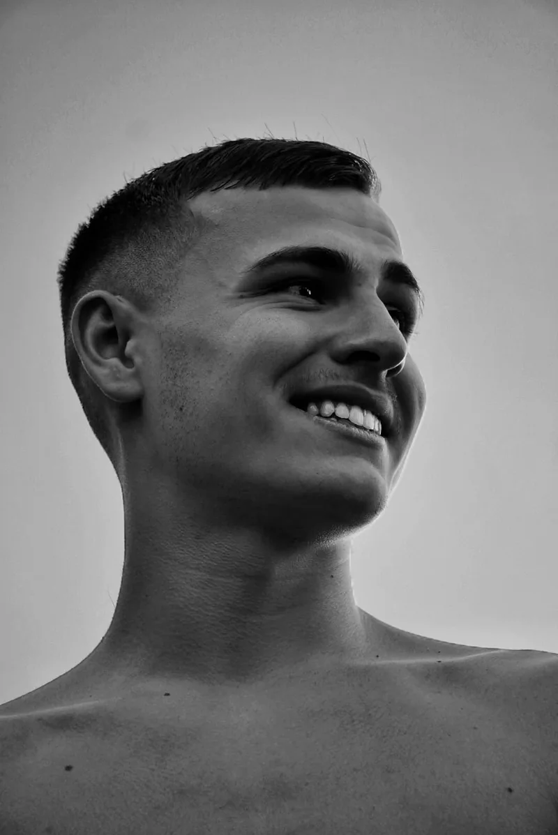 Portrait en noir et blanc d’un homme souriant de trois quarts, le regard vers le ciel