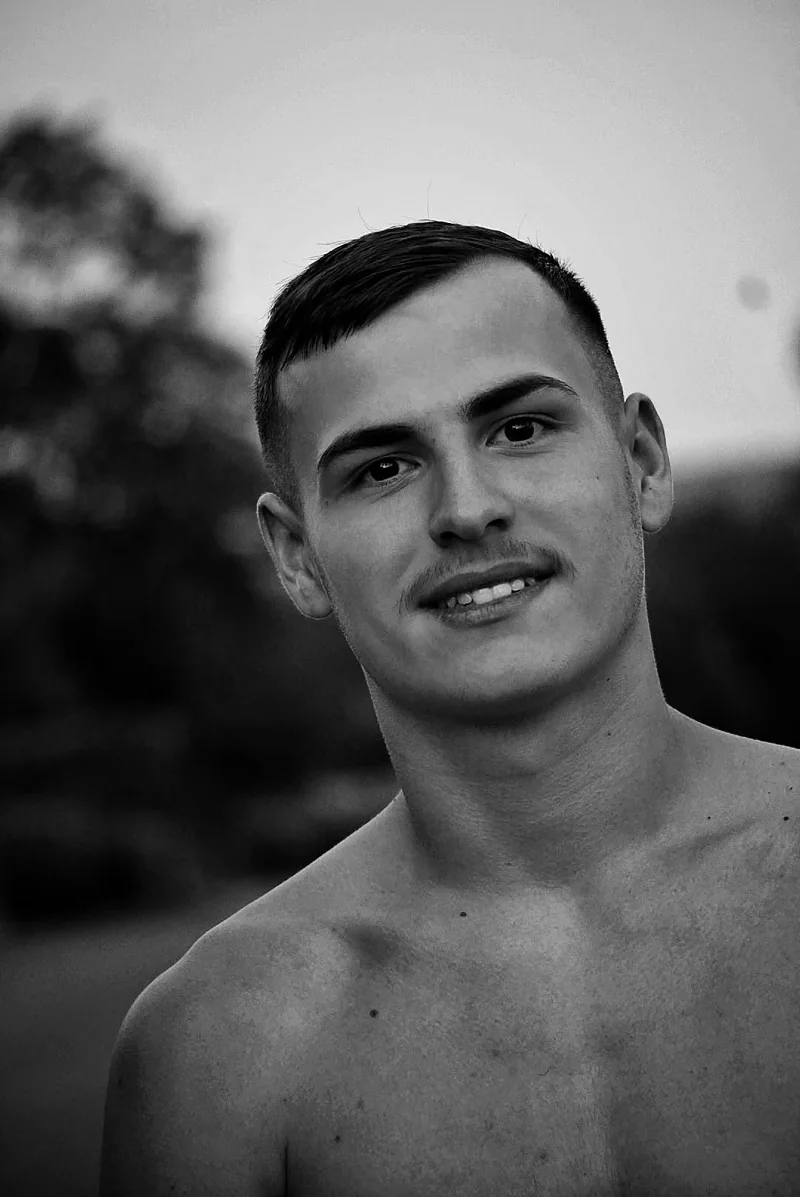 Portrait en noir et blanc d’un homme souriant, la tête légèrement inclinée