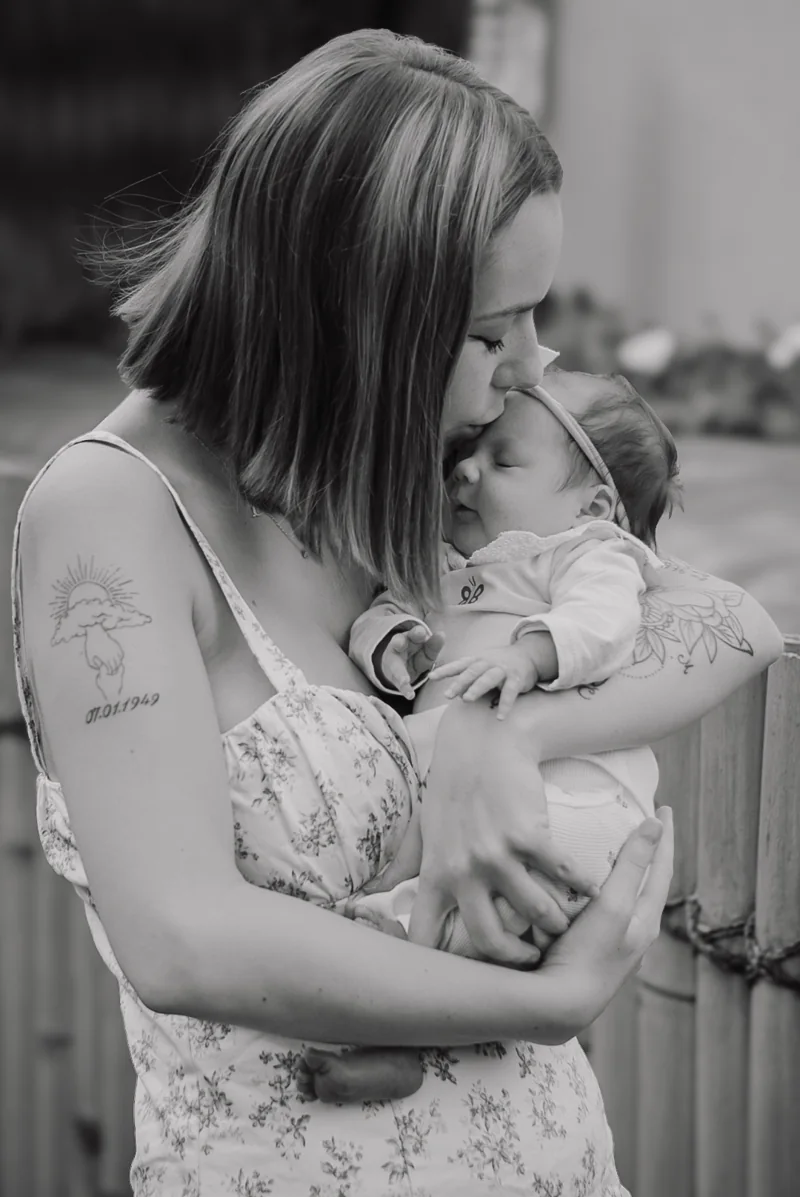 Une maman tient son nouveau-né contre elle, en noir et blanc