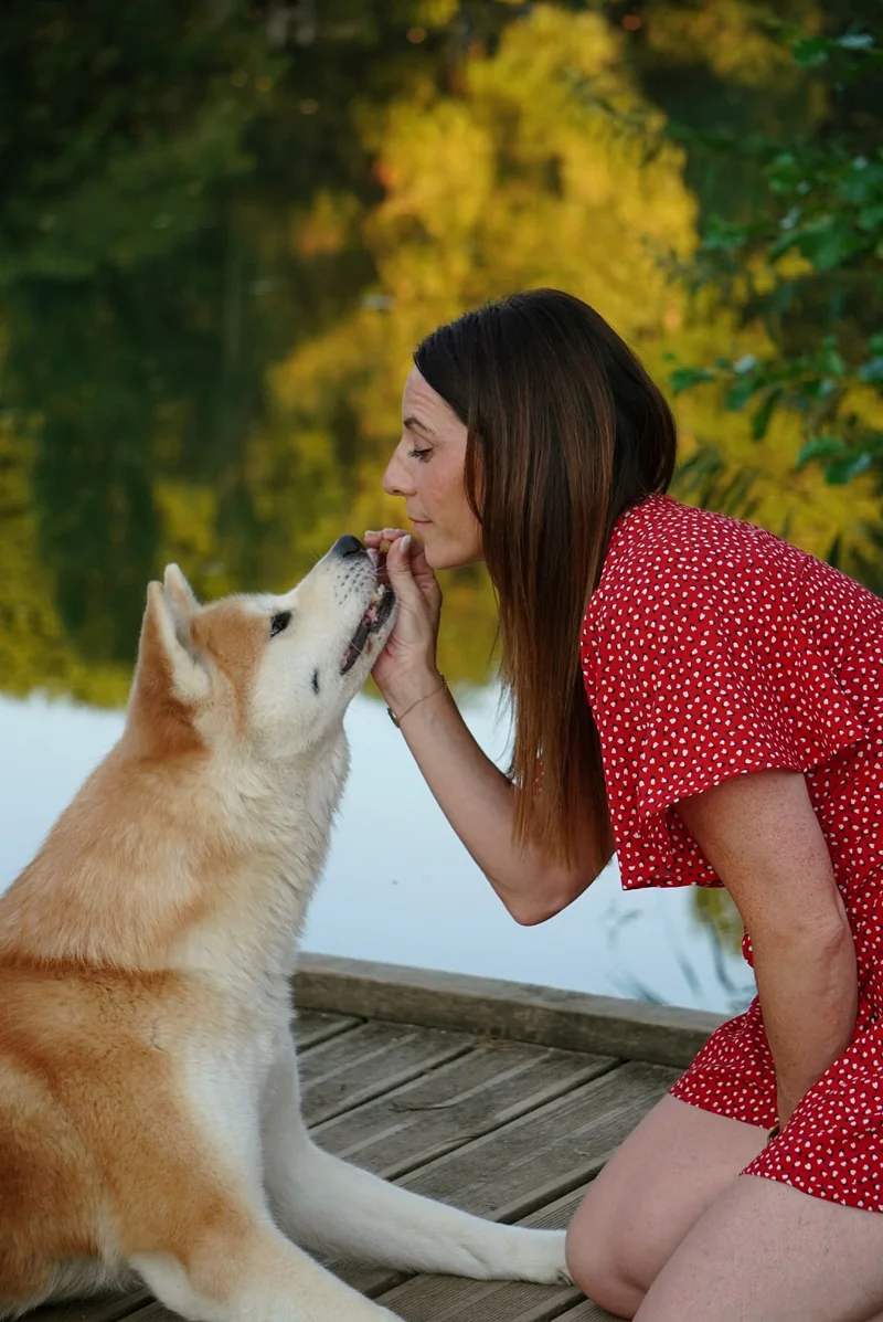 Un chien approche son museau du visage d’une femme sur un ponton