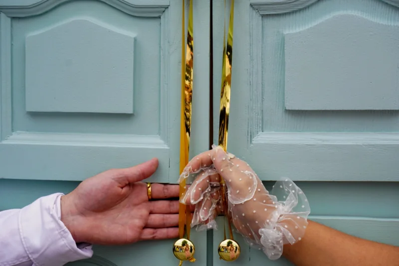 Deux mains tiennent des accessoires dorés devant des portes bleues